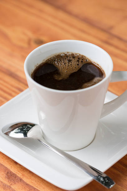 Cup of coffee with metal spoon on the table.