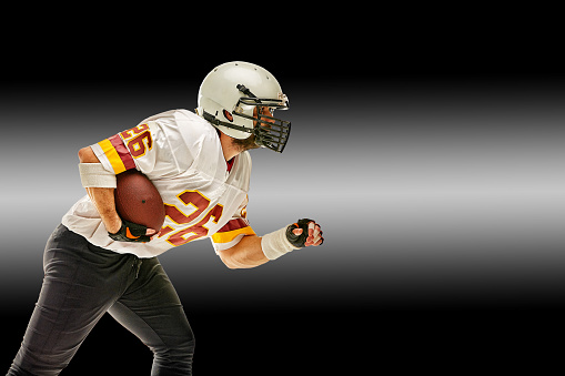 American football player in motion with the ball on a black background with a light line, copy space. The concept of the game is American football, movement. Black white background, copy space. sport banner.