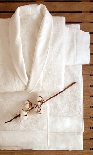 A cream bathrobe & towel set for men on a wooden background