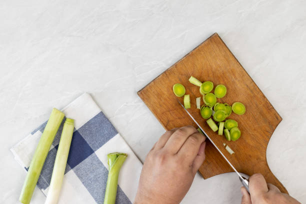 istock Cutting leak vegetable on the wooden board above grey marble table 1216481207