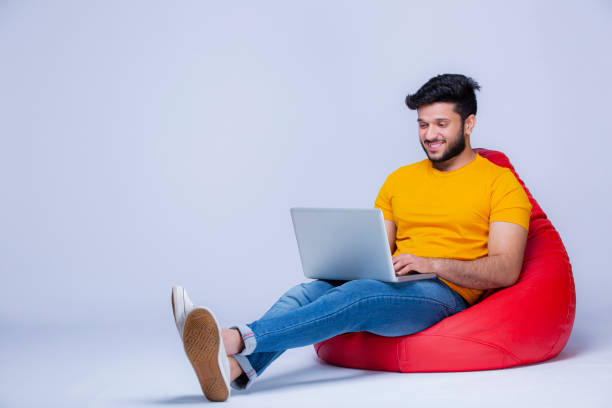 Young Men relaxing on bean bag chair on white background stock photo Background, Adult, Adults Only, Indian ethnicity, bean bag stock pictures, royalty-free photos & images