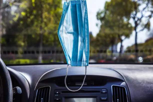 Photo of A disposable medical mask is hung on the front of the car