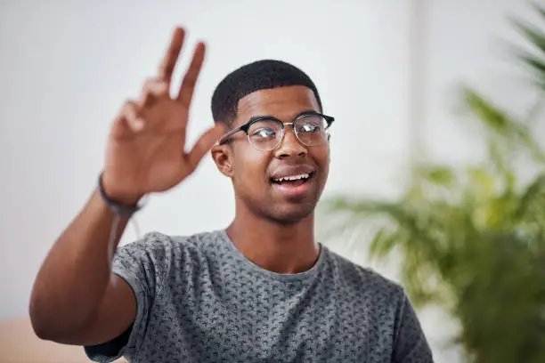 Shot of a young businessman raising his hand in an office