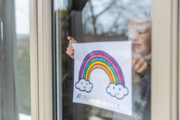 istock Young Boy sticking his drawing on home window during the Covid-19 crisis 1216489301
