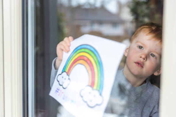 istock Young Boy sticking his drawing on home window during the Covid-19 crisis 1216489363