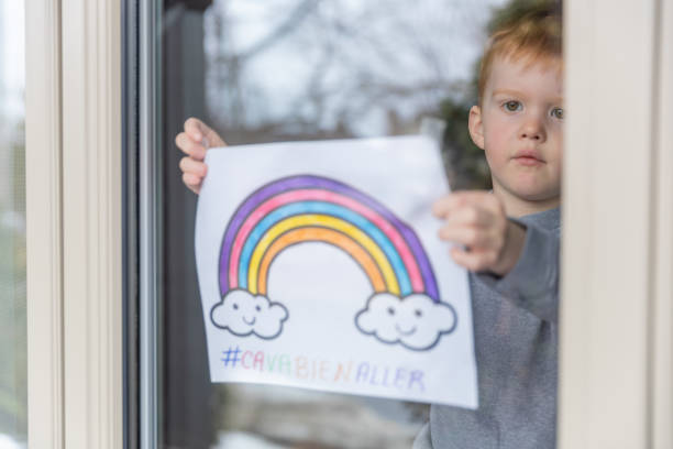 istock Young Boy sticking his drawing on home window during the Covid-19 crisis 1216489513