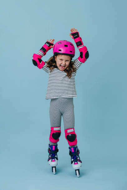 overemotional yelling little girl in roller skates wearing pink protective gear - overemotional imagens e fotografias de stock