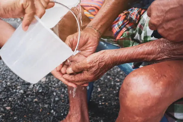 Photo of Person pour water on the hands of elders in family for doing respected and ask for blessing in Thai Songkran festival.