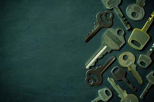 Different variety of vintage keys are placed on black wooden floor in darkness background. Closeup and copy space on left. Idea for keys to solving business problems. Concept for security or privacy.