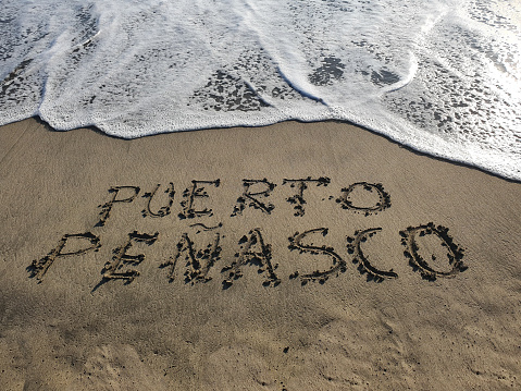 beach sand with text Puerto Penasco and a wave of the sea