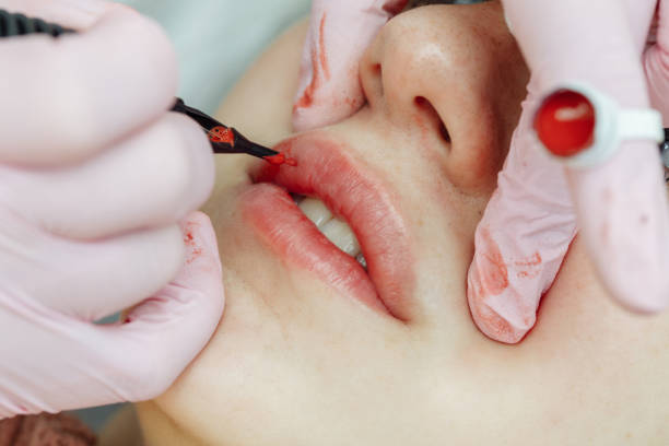 istock Woman having permanent makeup on lips in beauty salon 1216507398