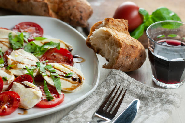 un plato con ensalada caprese junto con pan y vino - salad mozzarella food balsamic vinegar fotografías e imágenes de stock