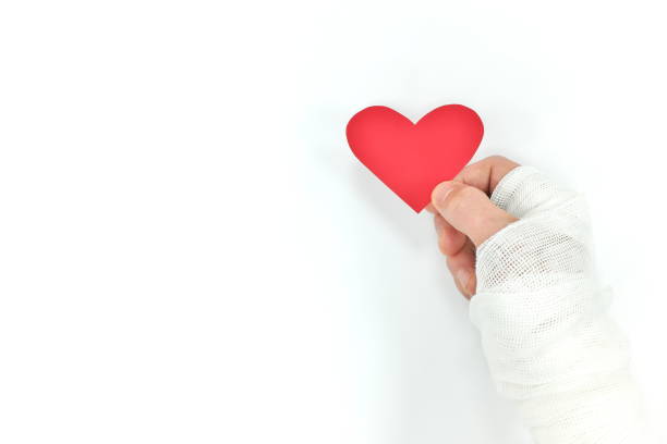 Injured hands holding a red heart in white background. Sacrificial and selfless love, genuine kindness and organ donation. Injured hands holding a red heart in white background. Sacrificial and selfless love, genuine kindness and organ donation. self sacrifice stock pictures, royalty-free photos & images