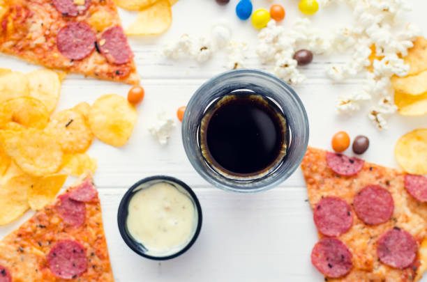 Fast food and unhealthy eating concept. Close up of fastfood snacks: pizza, popcorn, potato chips and candies. Assortment of carbohydrates products bad for figure, skin, heart and teeth. Top view.