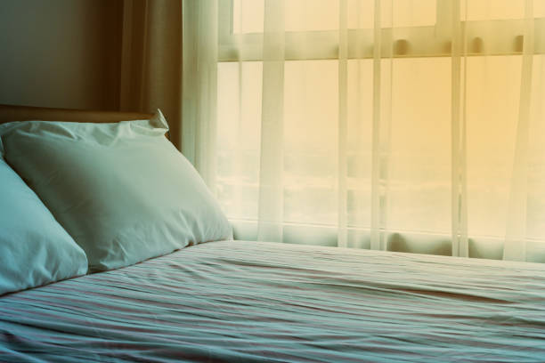 istock the top White pillows on a soft bed with pink sheets and orange light 1216517788