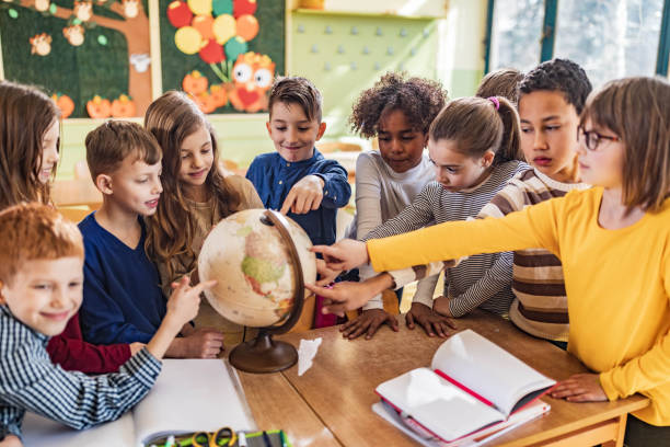 istock Large group of happy students analyzing globe in the classroom. 1216521280