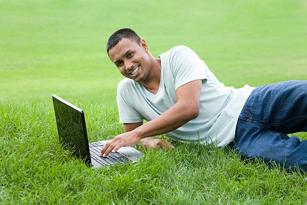 latino männliche tippen mit einem kabellosen laptops - dimple male human face men stock-fotos und bilder