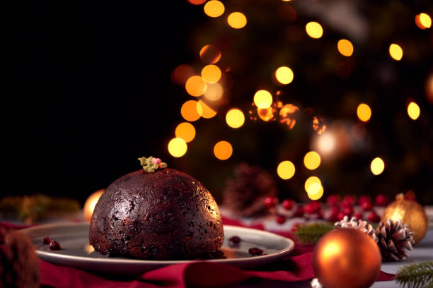 istock Traditional Christmas Pudding On Table Set For Festive Christmas Meal With Tree Lights In Background 1216523886