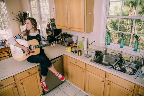 自宅のキッチンでギターを弾く女性 - model home house home interior plate ストックフォトと画像