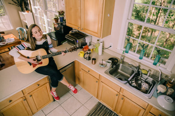 自宅のキッチンでギターを弾く女性 - model home house home interior plate ストックフォトと画像