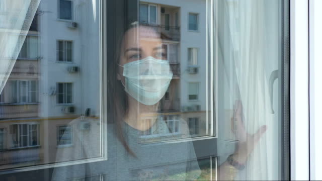 Woman in Quarantine Looking out the Window. Staying Home in Self-Quarantine