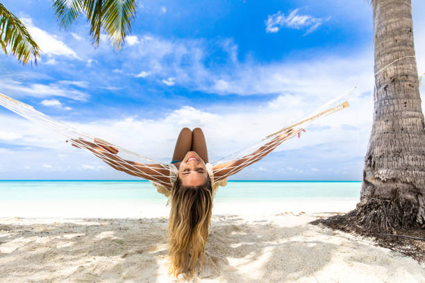 istock Happy woman having fun while lying in hammock on the beach. 1216527137