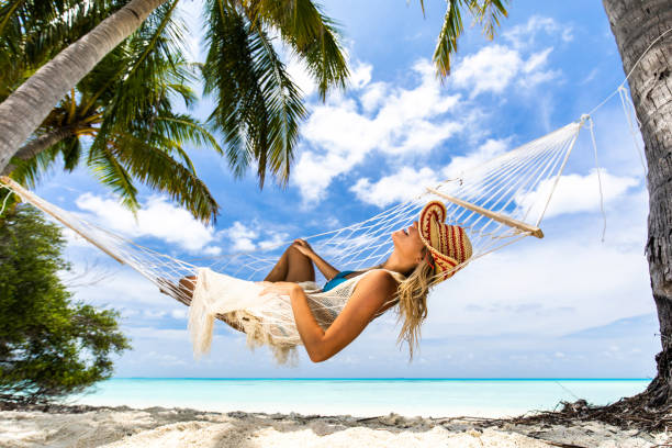 istock Happy woman spending her summer day in hammock on the beach. 1216527377