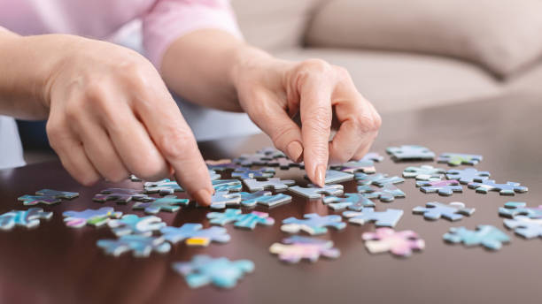 istock Senior woman playing jigsaw puzzle at home, empty space 1216529444