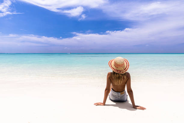 istock Back view of a woman looking at view from sandy beach. 1216529825
