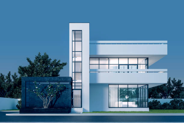 istock Modern house with white plaster with a balcony and a high staircase, in the cold evening light with warm light from the Windows against the background of trees and a white fence 3D stock illustration 1216530808