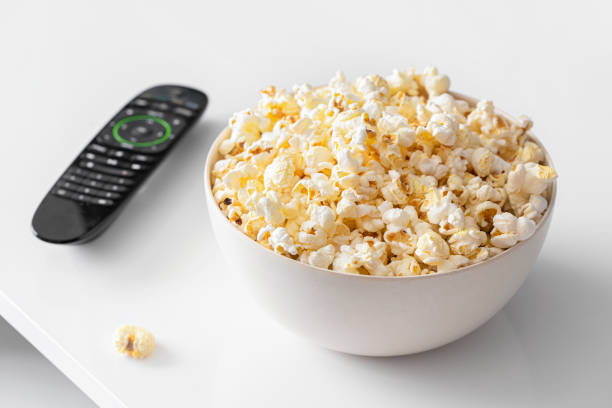 istock Popcorn bowl and remote control  on white table for Smart tv and home cinema concept. 1216530961