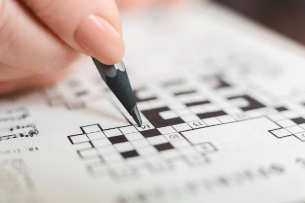 Senior woman completing crossword at home, close up Senior woman completing crossword during quarantine at home, close up crossword stock pictures, royalty-free photos & images