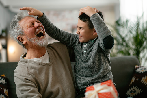 Grandpa giving his grandson birthday gift. Grandfather becomes present from grandchild.