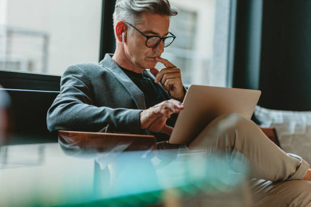オフィスロビーで電子メールを読むビジネスマン - using laptop businessman laptop business ストックフォトと画像