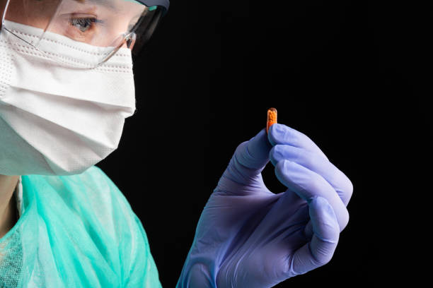 arzneimittelentwicklung - surgical glove human hand holding capsule stock-fotos und bilder