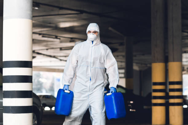 istock Man in virus protective suit holding two jerrycans with antiseptic 1216537471