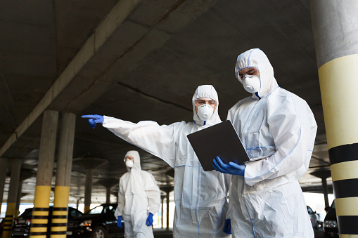 Hombres con trajes especiales de protección contra virus que investigan la disponibilidad de coronavirus photo