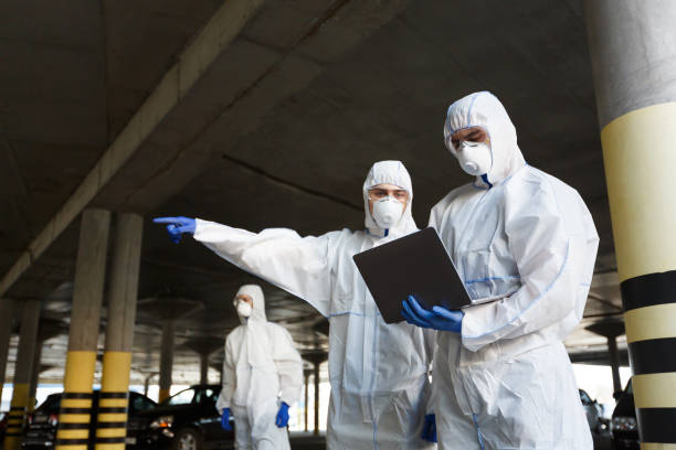 hombres con trajes especiales de protección contra virus que investigan la disponibilidad de coronavirus - traje protector fotografías e imágenes de stock