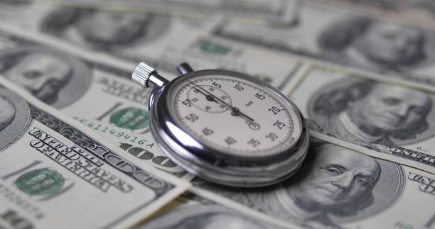 ストップウォッチはドルにあります。時間はお金の概念です。 - finance photography us currency stopwatch ストックフォトと画像