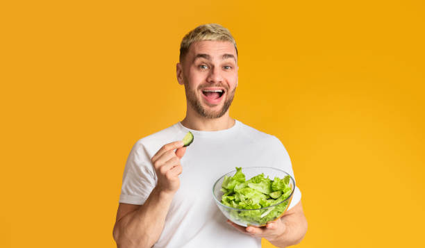 istock Man diet fun at studio. Happy guy eat vegetables 1216542143