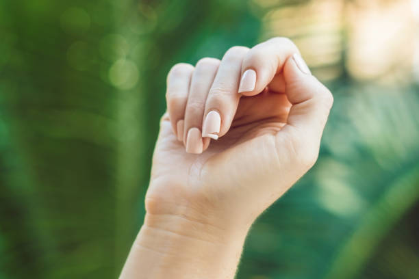 Broken nail on a woman's hand with a manicure on a green background stock photo