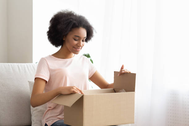 istock Satisfied young woman customer sit on sofa, unpack package parcel 1216542622