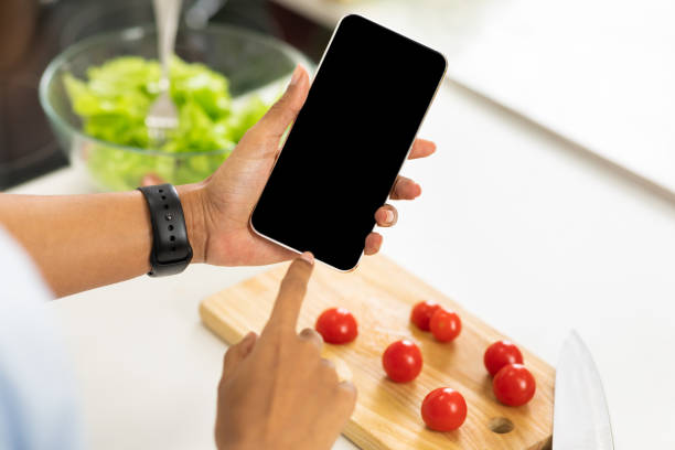 istock Afro girl using smartphone with blank screen in the kitchen 1216543914