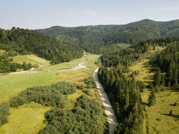 istock Road through mountains and forest captured from above 1216552632