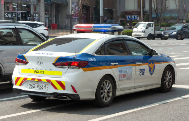Seoul, South Korea - May 16, 2015: Street protestors behind two Korean policemen in bright vest uniform, written police on back, supervising a peaceful protest on downtown street