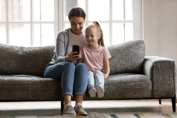 istock Pleasant nanny showing mobile educational application to kid girl. 1216554344