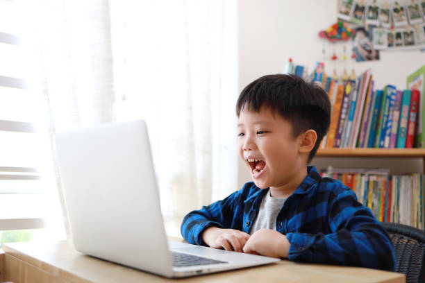 Boy using laptop for homework at home Portrait of little Asian boy using laptop at home, online, video chatting, education, E-learning concept. 8 9 years photos stock pictures, royalty-free photos & images
