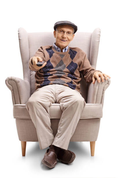 istock Senior man sitting in an armchair and using a tv remote control 1216559301