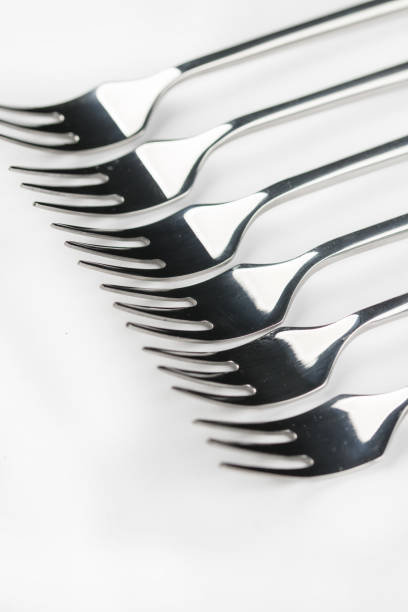 istock Selective focus closeup macro metal shiny forks lined up over white background 1216560392