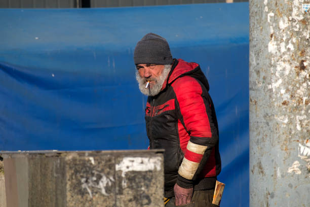 Bearded homeless man with a cigarette in his mouth and a stern look Vinnitsa, Ukraine - April 1, 2020: Bearded homeless man with a cigarette in his mouth and a stern look vinnytsia photos stock pictures, royalty-free photos & images